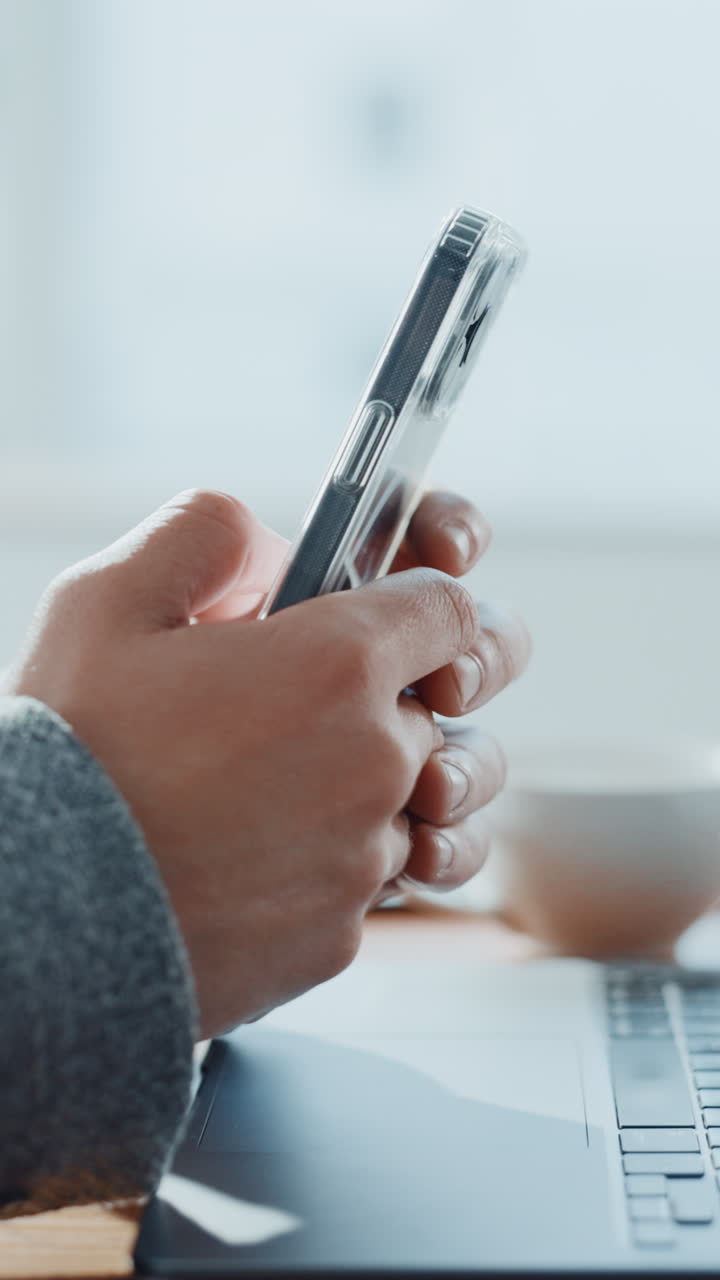 Close-up of Hands Holding a Smartphone in a Workspace