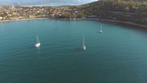 Aerial-view-of-three-sail-boat-in-a-clear-water-sea-bay-surrounded-by-wild-vegetation-in-east-Sardinia-coastline