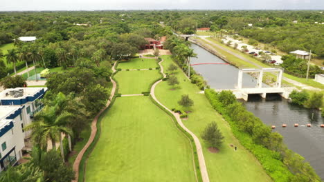 Dramatic-Aerial-Reveal-of-Manicured-Park-and-waterway