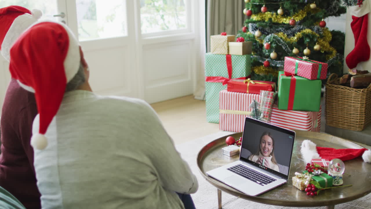 diversas amigas mayores que usan una computadora portátil para una videollamada de navidad con una mujer feliz en la pantalla