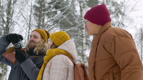 vista inferior de tres amigos vestidos de invierno hablando de algo que han visto en un bosque de invierno