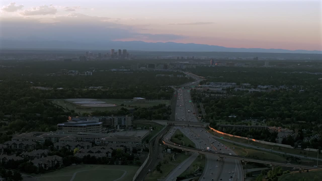 Downtown Denver i25 car truck traffic DTC Denver Tech Center Centennial cityscape aerial drone Colorado golden hour sunset clouds Lone Tree Aurora RTD lightrail Front Range Rocky Mountains down motion