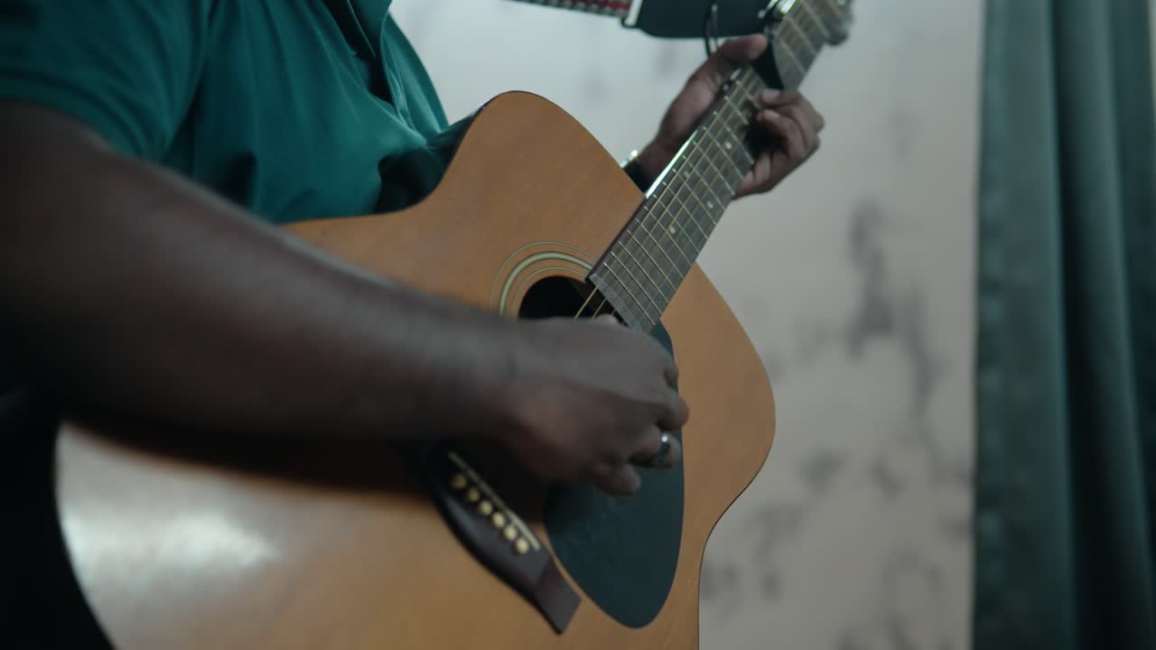 Primo piano di un uomo nero irriconoscibile che suona la chitarra acustica