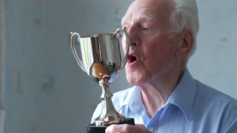un anciano caucásico inspeccionando su trofeo.