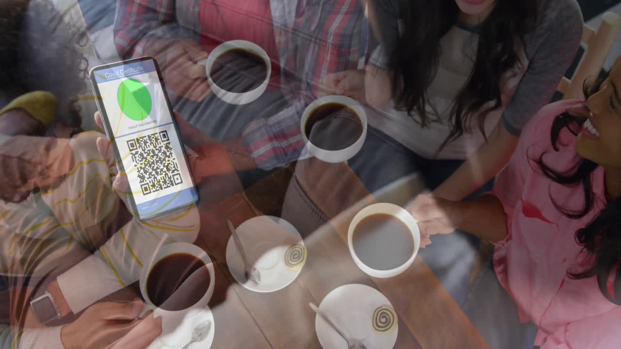 mujer sosteniendo un teléfono inteligente con código qr en la pantalla contra un grupo de amigos tomando café juntos