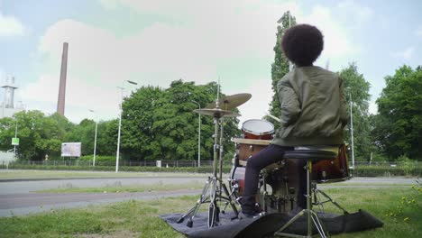 joven músico entusiasta aislado tocando la batería afuera