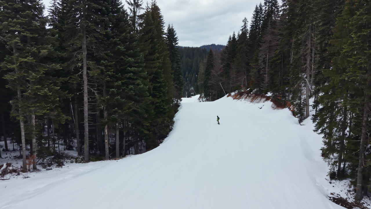 Sci su una pista innevata circondata da alberi alti in una località di montagna durante l'inverno.