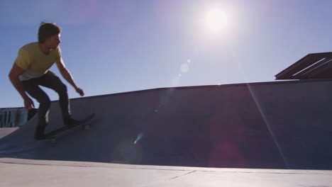 caucasian man riding and jumping on skateboard on sunny day