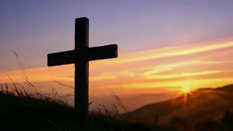 una cruz de madera se encuentra en la cima de una colina, enmarcada por una puesta de sol vibrante con tonos de naranja, amarillo y púrpura en el cielo