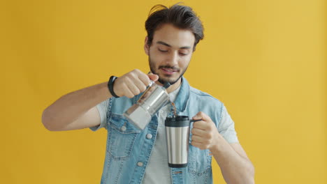 man pouring coffee from a moka pot into a travel mug
