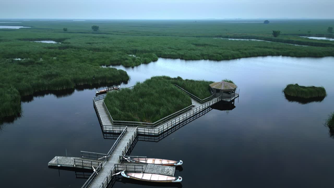 Drone circles boardwalk over marsh in fog with island gazebo