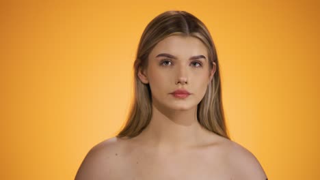 disparo medio de una mujer joven y bonita atractiva rasgando su cabello y sonriendo felizmente a la cámara porque ella está feliz frente al fondo amarillo en cámara lenta