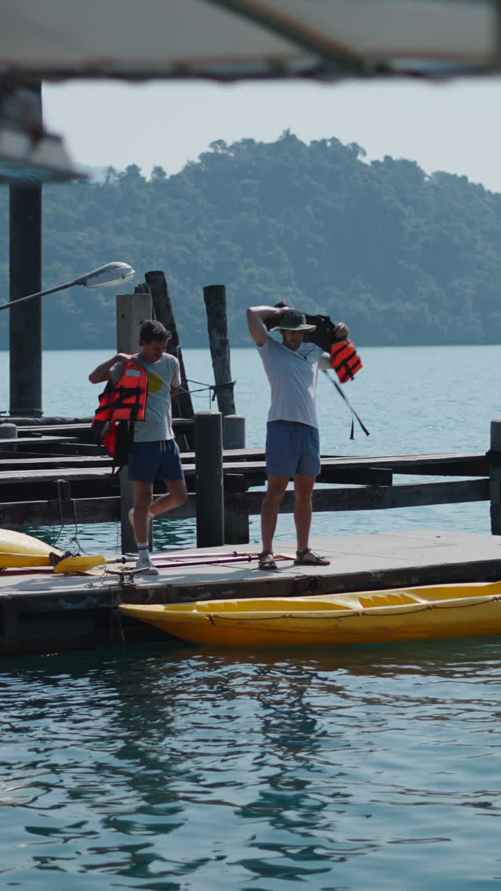 Persone su un molo con giubbotti di salvataggio e un kayak