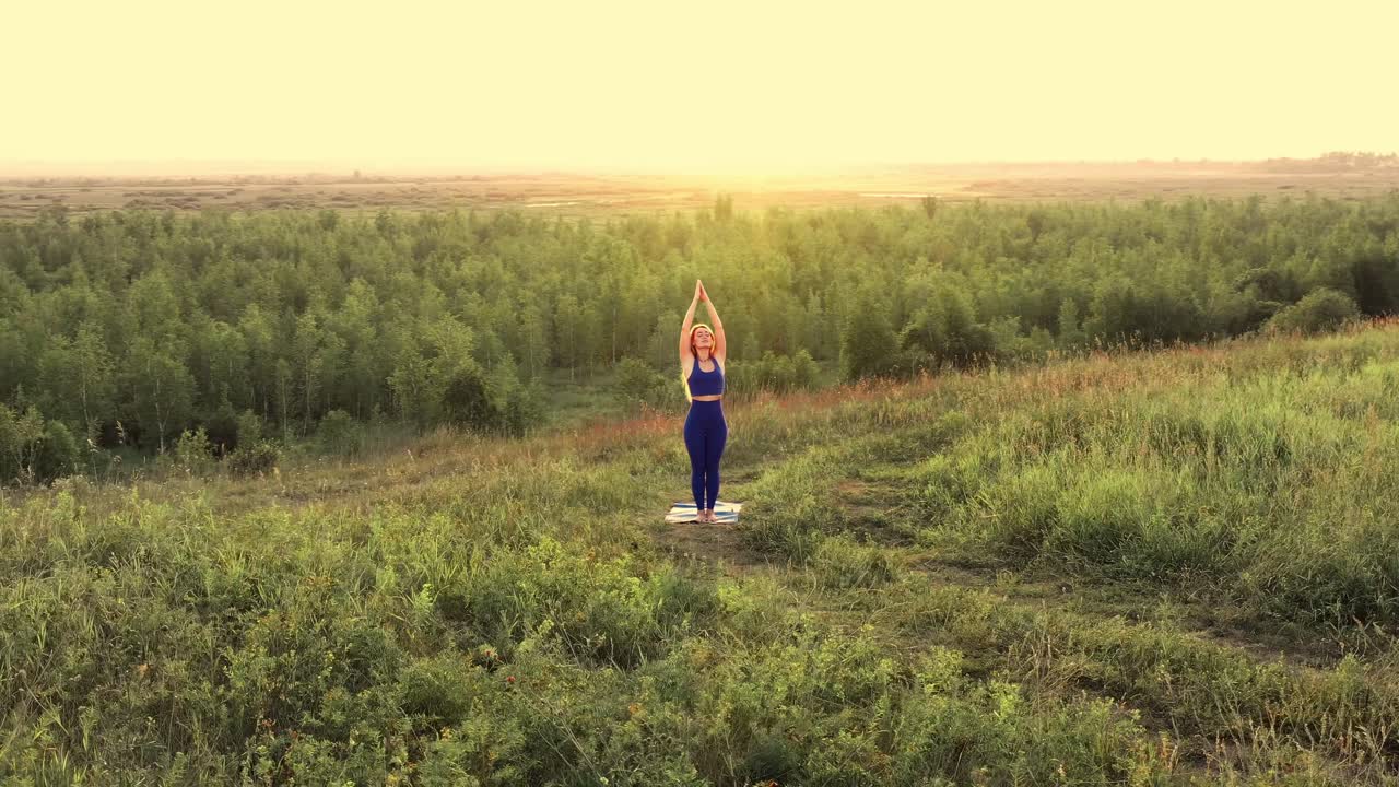 Donna che pratica yoga in un campo al tramonto