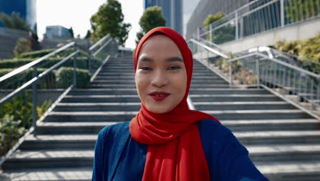 young muslim woman in red hijab taking selfies and vlogging outdoors