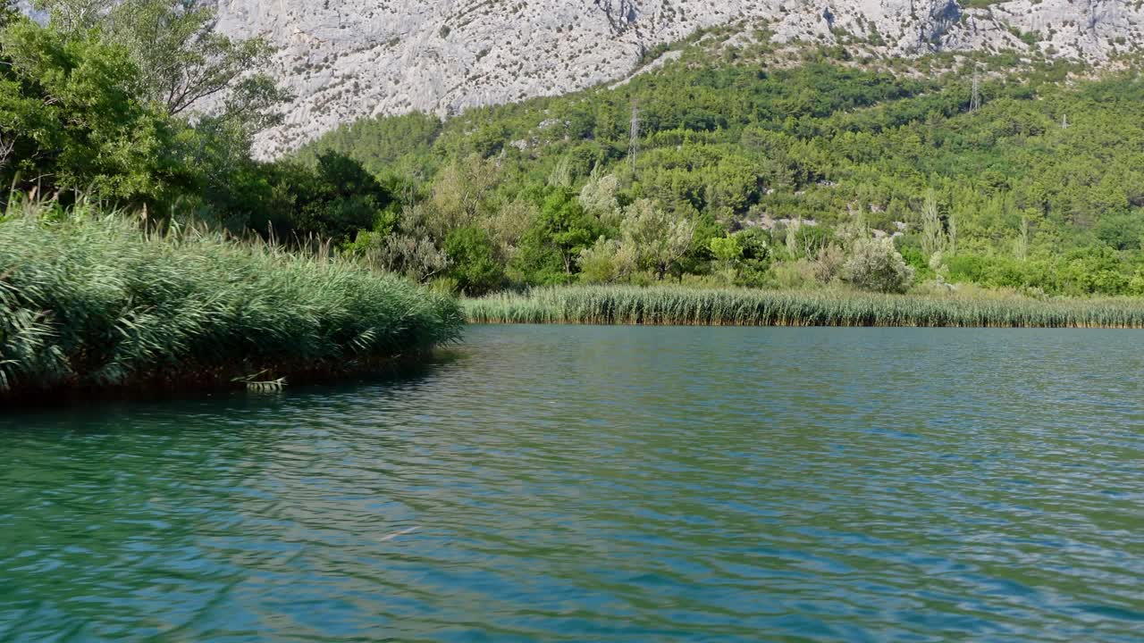foto de mano que muestra el río cetina y las montañas circundantes en omis, croacia, con una vista panorámica y una vegetación exuberante