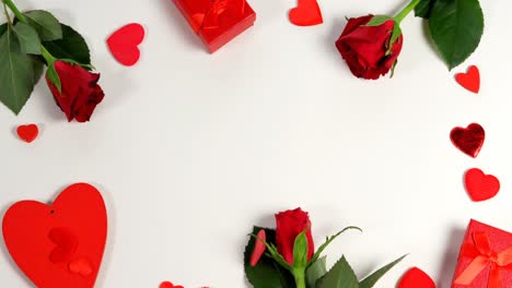 Red-roses,-gift-boxes-and-heart-shape-of-confetti-on-white-surface-in-circle-formation-4k