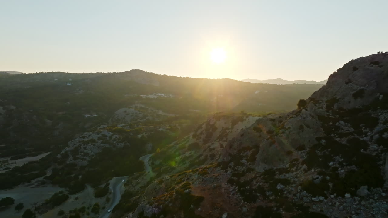 Aerial view tilting over mountains, toward the sunset sun in Rhodes, Greece