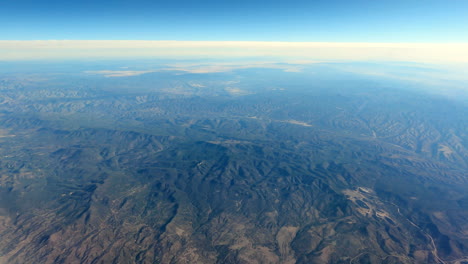 flying over mountainous terrain, clear sky, blue atmosphere