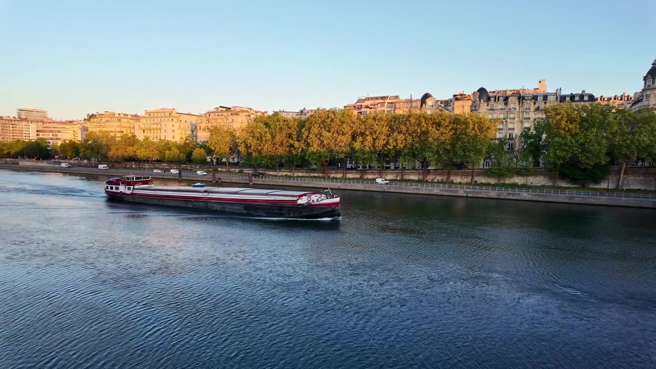 Traditional barge, or péniche, sailing on Seine river during beautiful golden hour in Paris, France. Copy space
