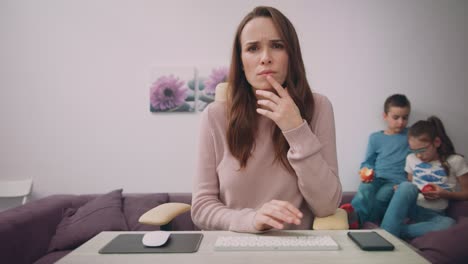 Business-mother-face-looking-at-monitor-with-kids-playing-on-background