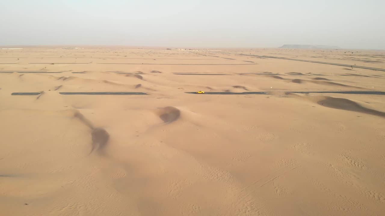 아랍 에미레이트 두바이의 모래로 뒤덮인 사막 도로 한가운데 스포츠카 드론으로 공중 원형 촬영