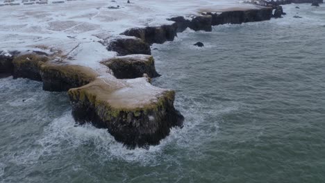 ocean waves hitting the rocky cliff and coastline of arnarstapi in iceland