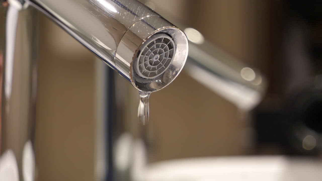Rubinetto che perde gocciolando acqua, riflesso nello specchio del bagno, primo piano.