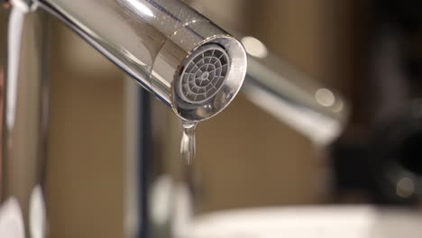 grifo con fugas goteando agua, reflejo en el espejo del baño, cerrar