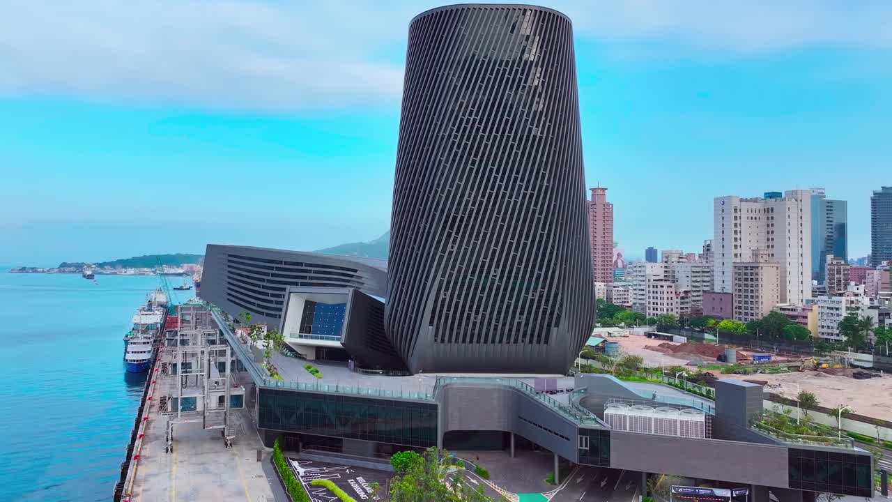 Slow aerial orbit showing modern building of Cruise Terminal in Kaohsiung during blue sky at port