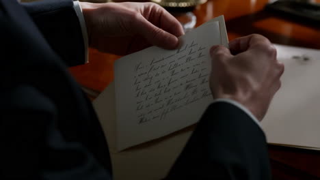 a person's hands holding and reading a handwritten letter