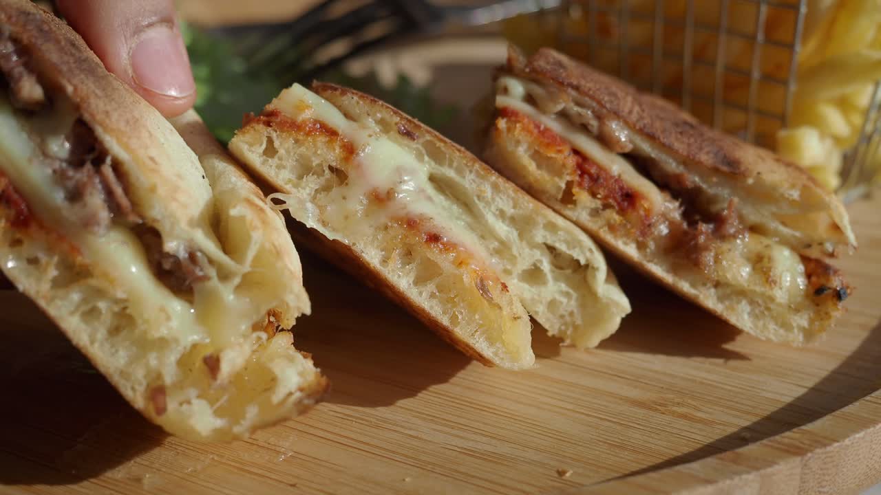 Mano recogiendo un delicioso sándwich panini con queso derretido