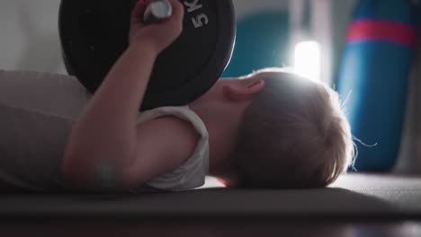 strong boy holds barbell in hands turning head to light