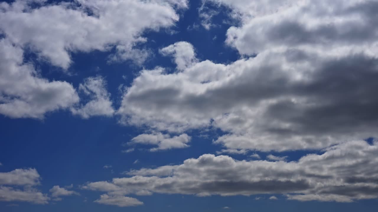 A dramatic time lapse in the sky where thick storm clouds begin to cover patches of blue. The contrasting tones highlight the transition between clear and stormy weather.