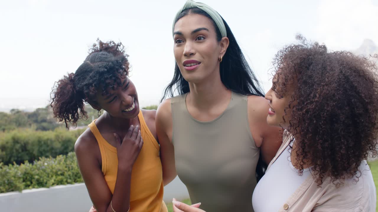 Amigas africanas rindo enquanto a mulher do centro conta uma história no pátio, com tiara e brincos de argola dourados.