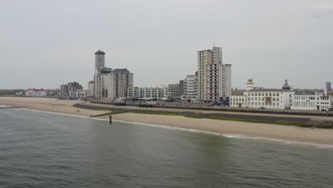 Aerial-dolly-panorama-of-a-waterfront-skyline-and-an-empty-city-beach-in-Vlissingen,-Zeeland,-The-Netherlands