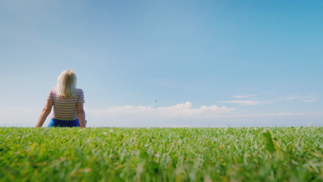 woman relaxes in nature sitting in a picturesque place on a green meadow