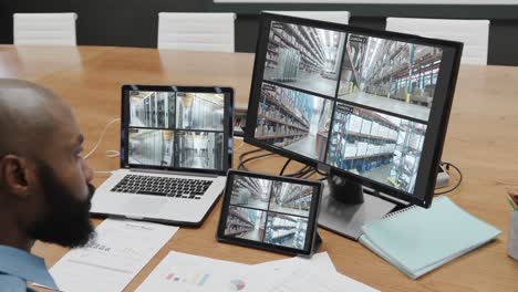 african american male security officer with business cctv camera views on three screens, slow motion