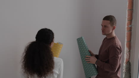 young couple decorating their new home with wallpaper