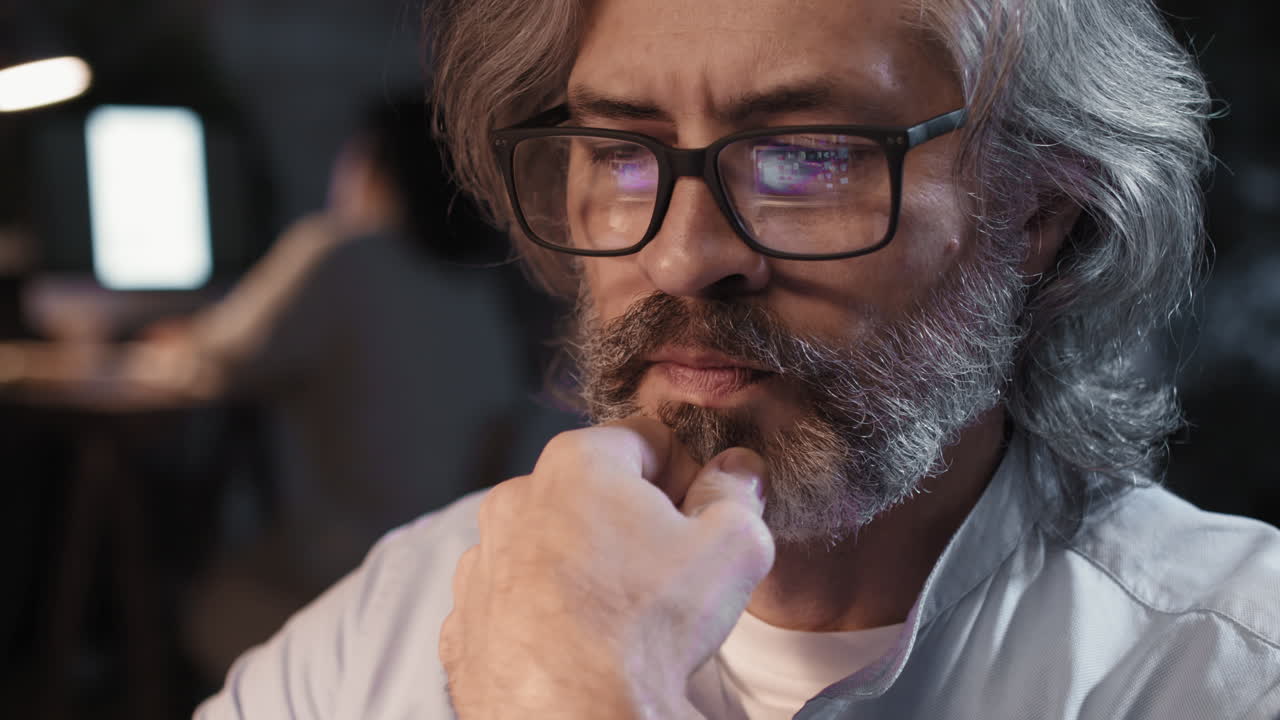 Close-up of a Thoughtful Senior Man with Glasses Reflecting a Screen