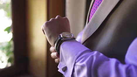 man in a suit adjusting his wristwatch, showcasing a formal and polished style