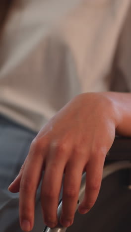 woman with disability with physical injuries sits in wheelchair on blurred background. caretaker pushes assistive equipment with disabled patient closeup