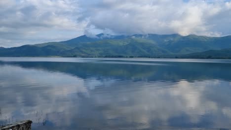 scenic view of kerkini reservoir in northern greece on a chilly spring day, with surrounding mountains and a cloudy sky reflecting in the still, clear waters