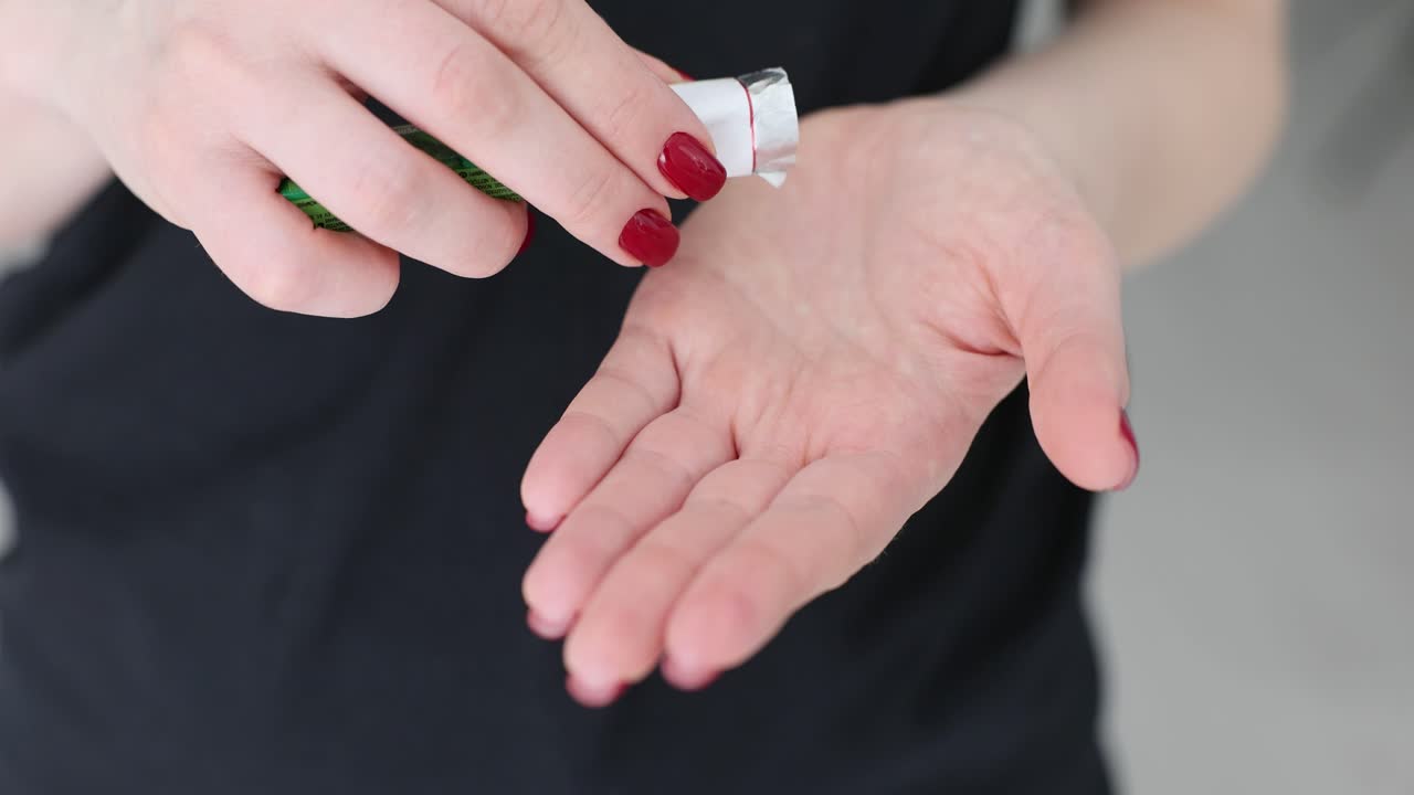 Close-up of a person dispensing toothpaste from a tube into their hand