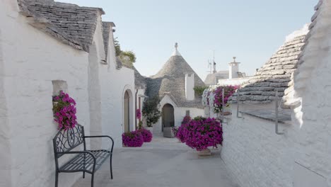 Callejón-De-Trulli-Blanco-En-Alberobello-Con-Flores-De-Buganvilla