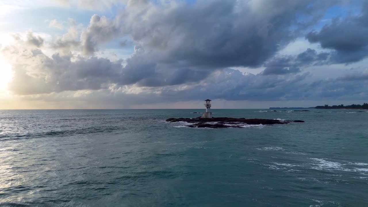 Lighthouse on a rocky island in the sea under cloudy skies