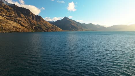 panoramic aerial overview of brown rocky cliffs sloping into lake wakatipu