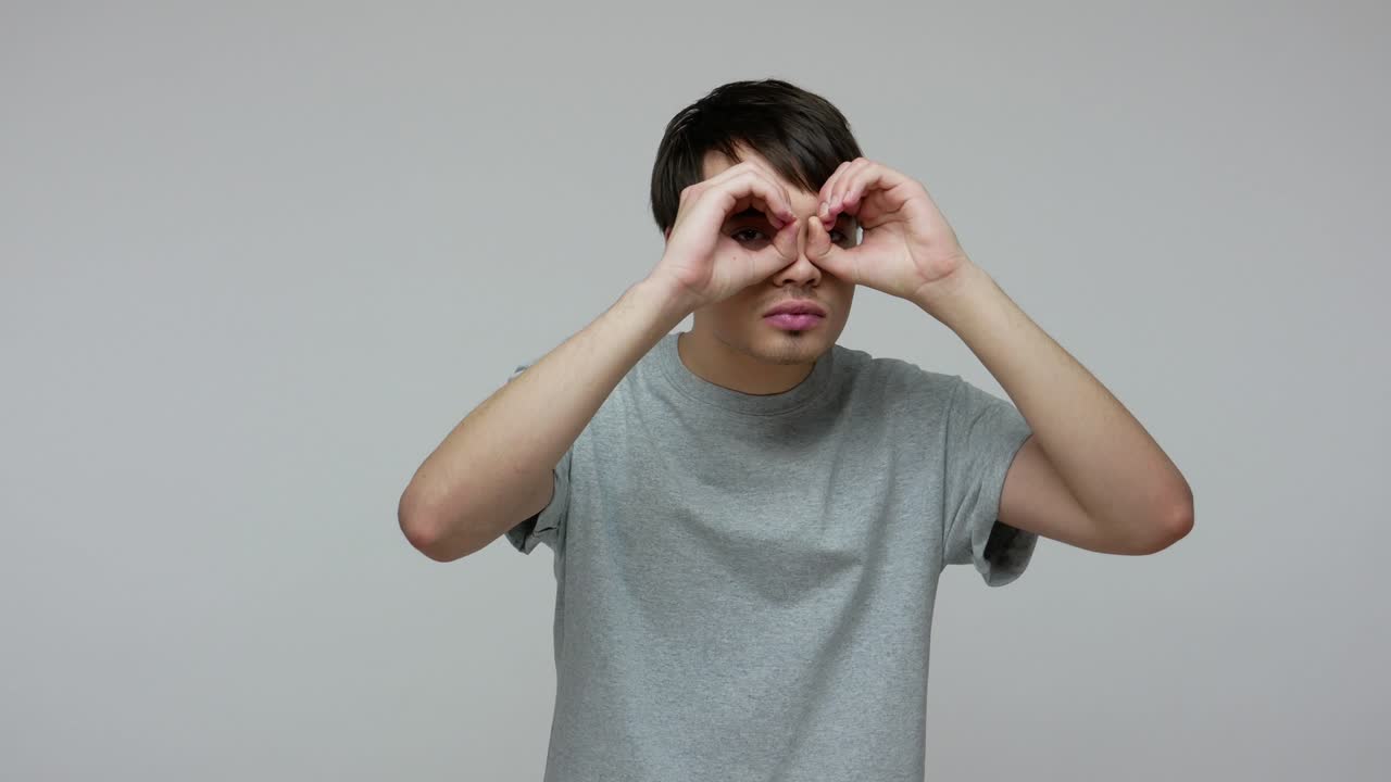 안경에 손을 들고 있는 젊은 남자가 주위를 관찰하며, 심각한 주의 깊은 시선으로 충격을 표현하고 있다.