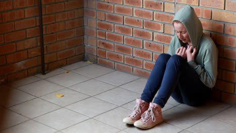 sad schoolgirl sitting alone on floor