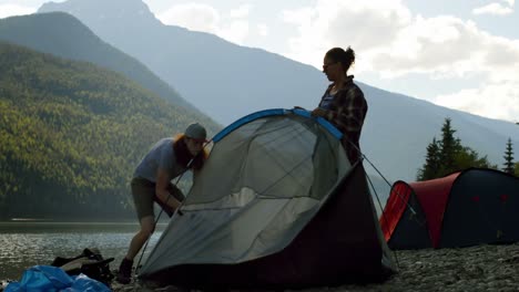 couple setting up tent near riverside 4k